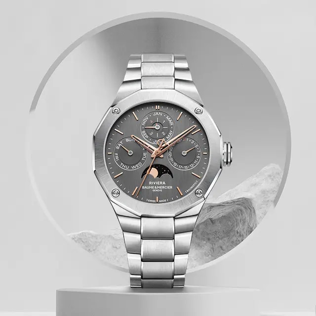 A watch with grey shield and a steel strap