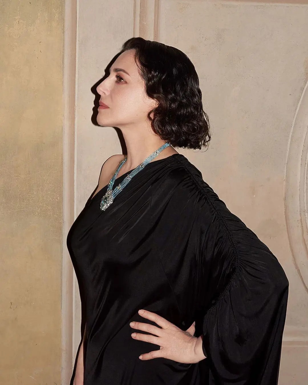 A woman in black dress wearing a necklace with diamonds